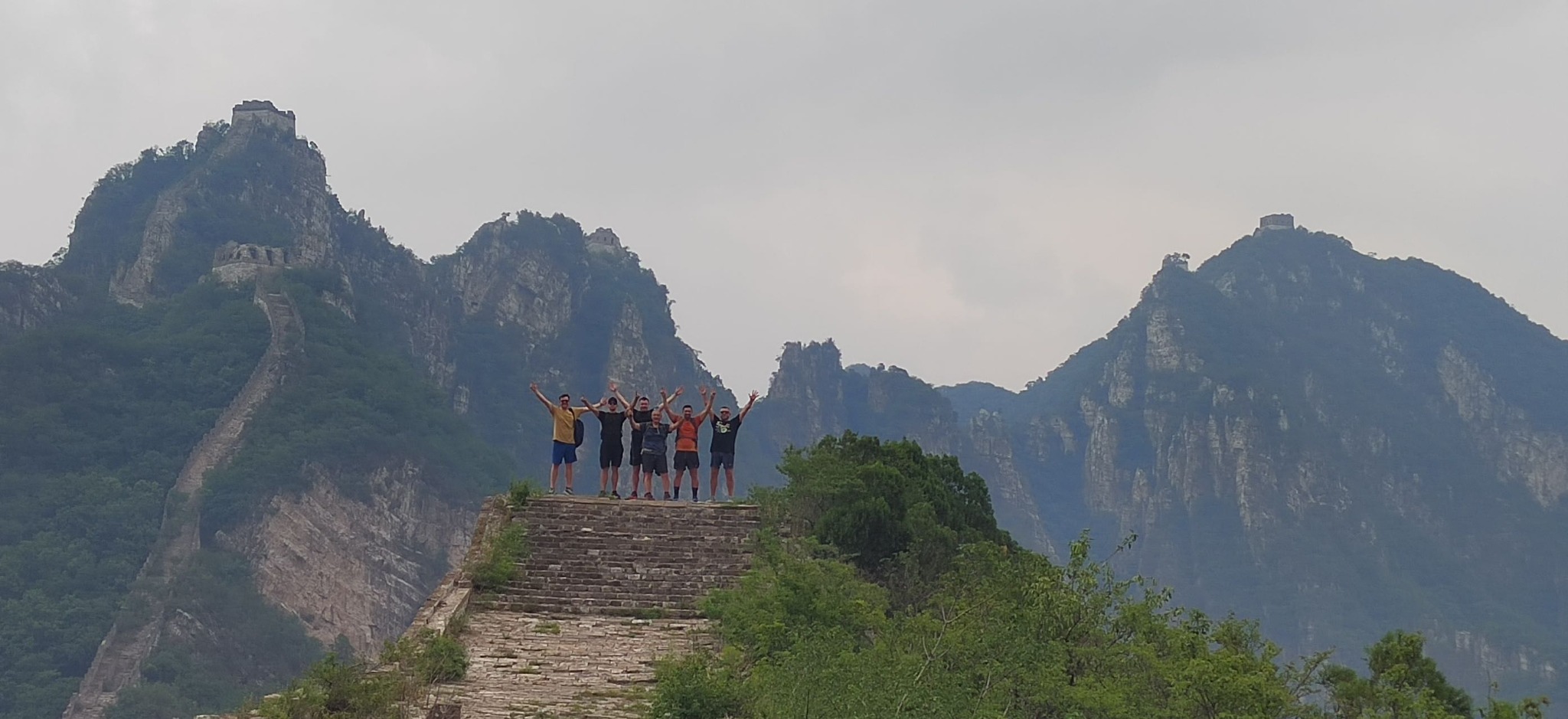 Hikers celebrating on the Great Wall surrounded by dramatic mountain peaks